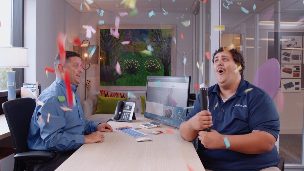 two guys in an office setting off a confetti cannon
