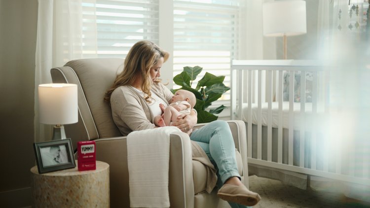 mother holding baby in a rocking chair with Novaferrum box on side table