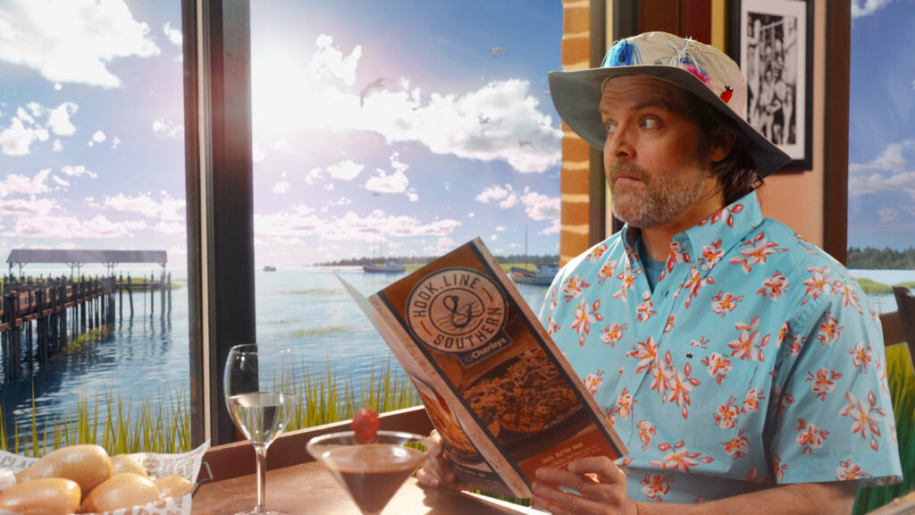 customer at O'Charley's restaurant opening his menu near a window that looks out over the beach