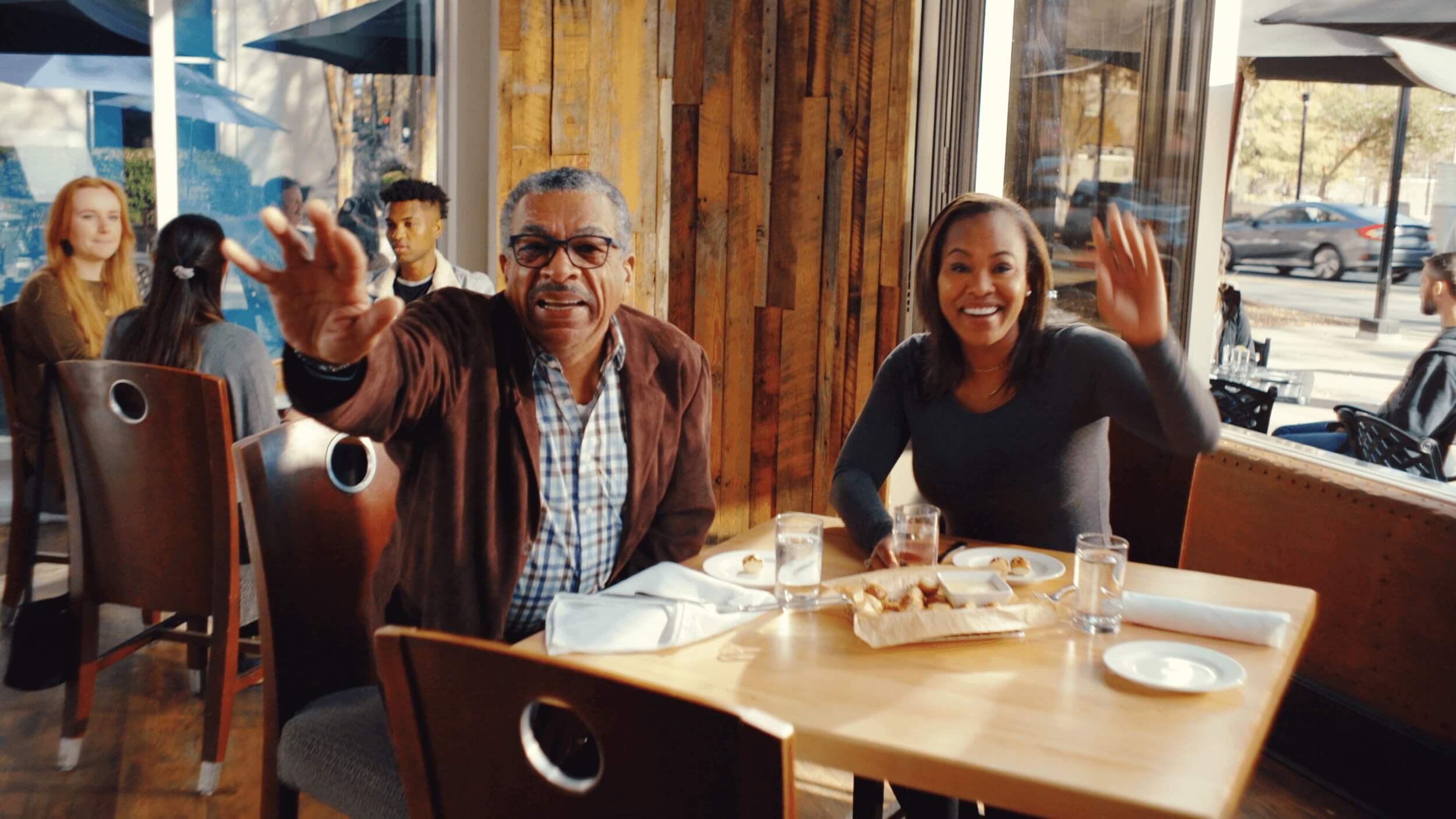 couple waving to friends in a restaurant