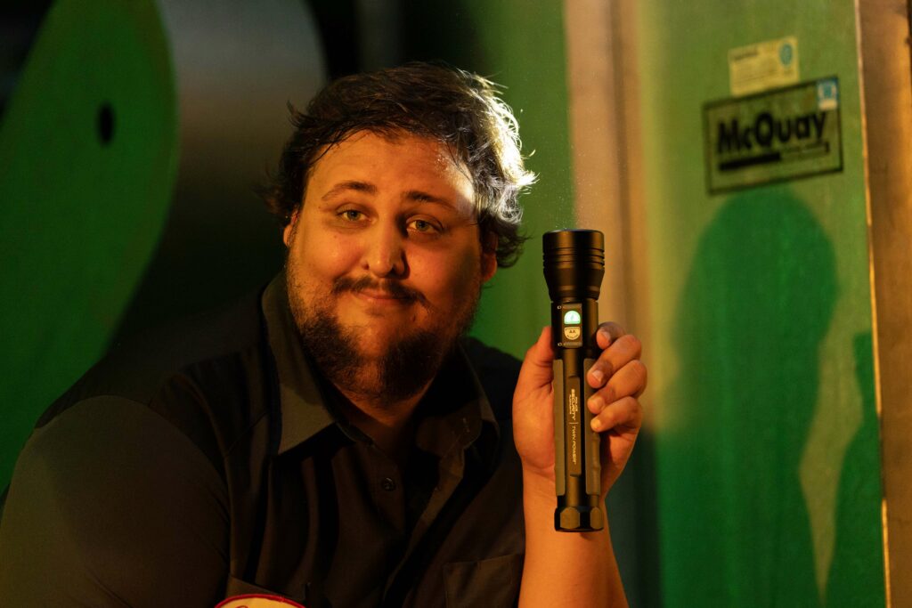 a man poses with a flashlight